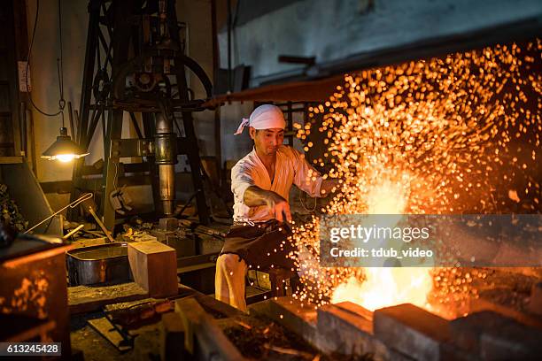 japanese blacksmith stokes a fire preparing to forge a sword - sword bildbanksfoton och bilder