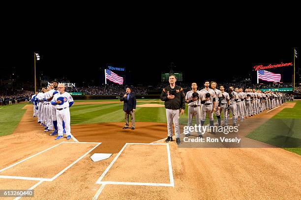 Members of the Chicago Cubs and the San Francisco Giants are seen on the base path during the singing of the national anthem prior to Game 1 of NLDS...