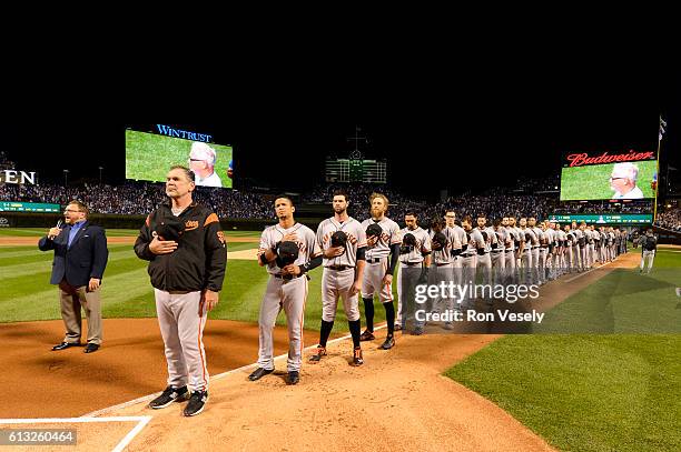 Members of the San Francisco Giants are seen on the base path during the singing of the national anthem prior to Game 1 of NLDS against the Chicago...