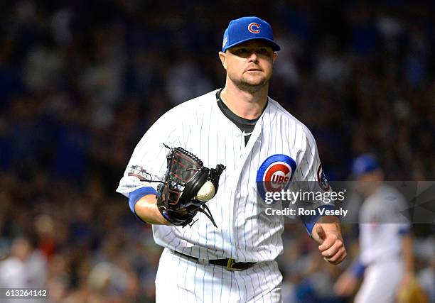 Jon Lester of the Chicago Cubs jogs to first with the ball stuck in the webbing of his glove to force out Buster Posey of the San Francisco Giants at...