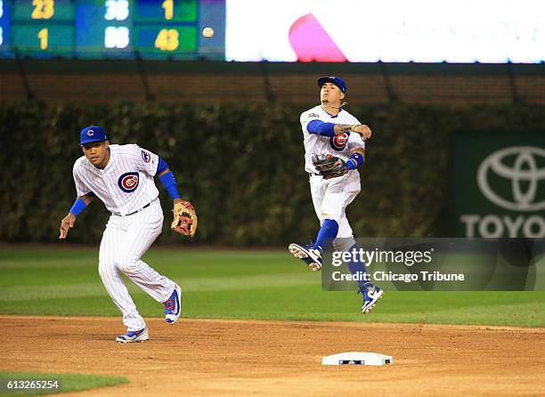 Chicago Cubs second baseman Javier Baez, right, throws over Chicago Cubs shortstop Addison Russell after bobbling a grounder in the second inning...