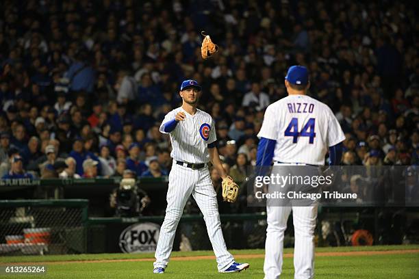 Chicago Cubs third baseman Kris Bryant helps first baseman Anthony Rizzo switch gloves in the third inning against the San Francisco Giants in Game 1...