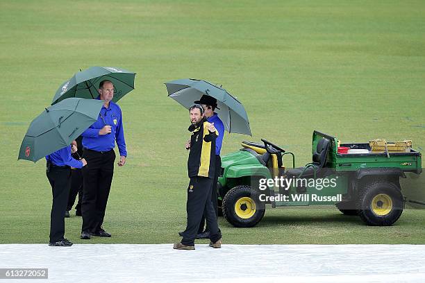 Match officials speak to ground staff after a heavy shower delays the start of play during the Matador BBQs One Day Cup match between Western...