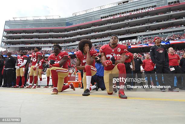 Eli Harold, Colin Kaepernick and Eric Reid of the San Francisco 49ers kneel on the sideline during the National Anthem prior to the game against the...