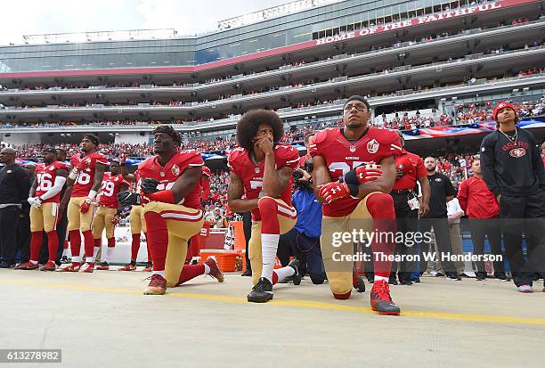 Eli Harold, Colin Kaepernick and Eric Reid of the San Francisco 49ers kneel on the sideline during the National Anthem prior to the game against the...