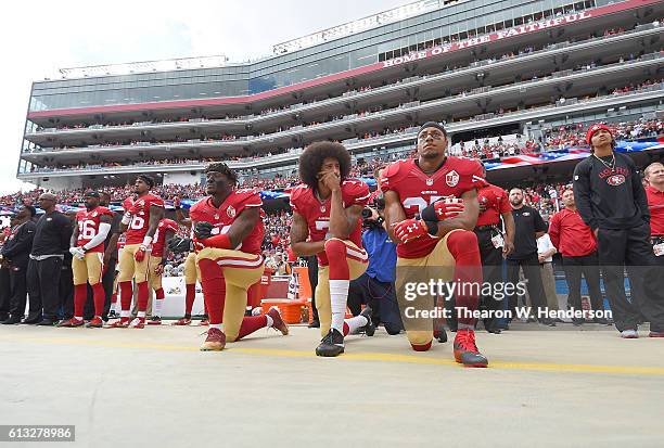 Eli Harold, Colin Kaepernick and Eric Reid of the San Francisco 49ers kneel on the sideline during the National Anthem prior to the game against the...