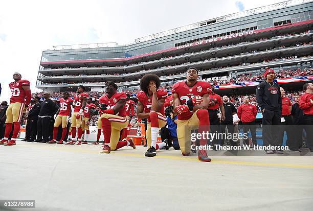 Eli Harold, Colin Kaepernick and Eric Reid of the San Francisco 49ers kneel on the sideline during the National Anthem prior to the game against the...