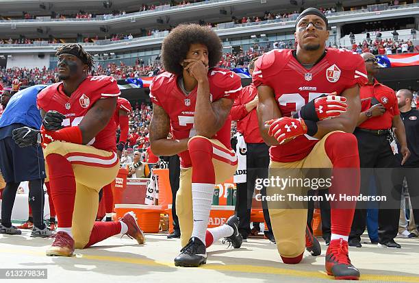 Eli Harold, Colin Kaepernick and Eric Reid of the San Francisco 49ers kneel on the sideline during the National Anthem prior to the game against the...
