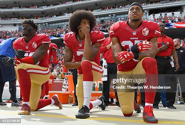 Eli Harold, Colin Kaepernick and Eric Reid of the San Francisco 49ers kneel on the sideline during the National Anthem prior to the game against the...