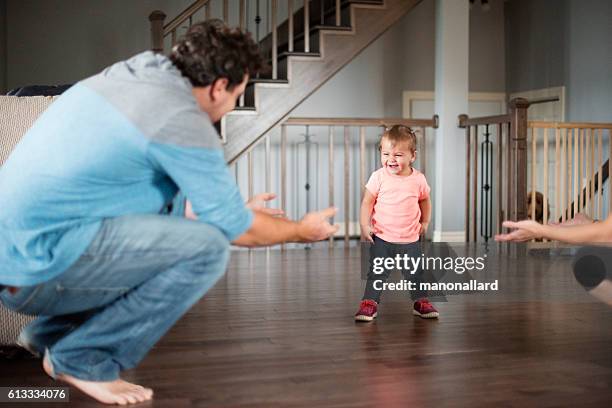 baby girl's first steps with her parents - dad baby dog stock pictures, royalty-free photos & images
