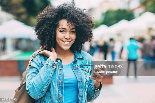 smiling young woman with smart phone - creole ethnicity stockfoto's en -beelden
