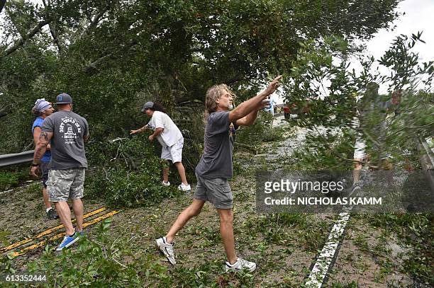 People remove tree limbs from a tree blocking access to the Frederick Hhn Bridge leading to Tybee Island in Savannah, Georgia, on October 8, 2016...