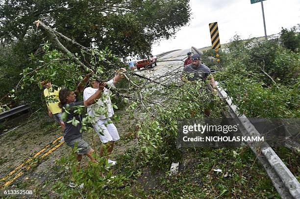 People remove tree limbs from a tree blocking access to the Frederick Hhn Bridge leading to Tybee Island in Savannah, Georgia, on October 8, 2016...