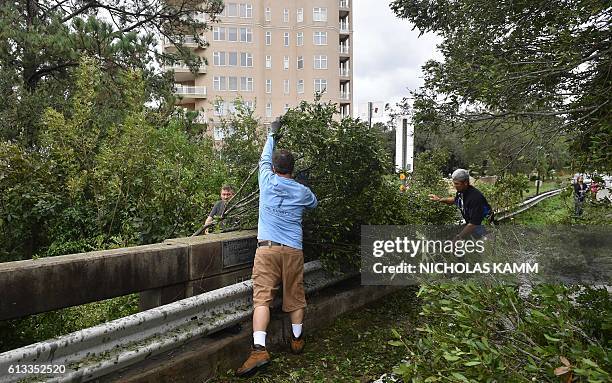 People remove tree limbs from a tree blocking access to the Frederick Hhn Bridge leading to Tybee Island in Savannah, Georgia, on October 8, 2016...