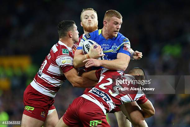 Jack Hughes of Warrington Wolves is tackled by Ben Flower and Willie Isa of Wigan Warriors during the First Utility Super League Final between...