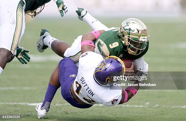 Defensive back Devon Sutton of the East Carolina Pirates tackles quarterback Quinton Flowers of the South Florida Bulls during the 1st quarter at...