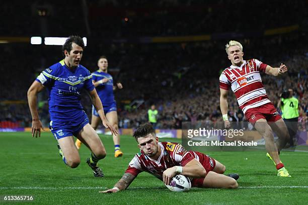 Oliver Gildart of Wigan scores his sides opening try despite the attention of Stefan Ratchford of Warrington during the First Utility Super League...