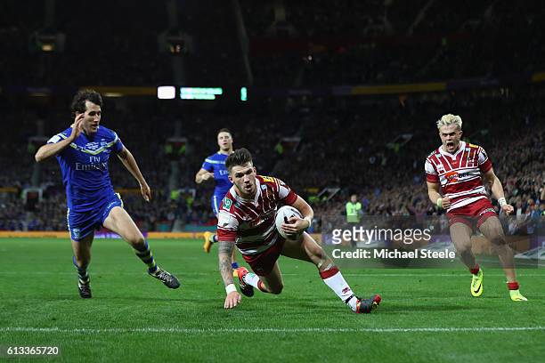 Oliver Gildart of Wigan scores his sides opening try despite the attention of Stefan Ratchford of Warrington during the First Utility Super League...