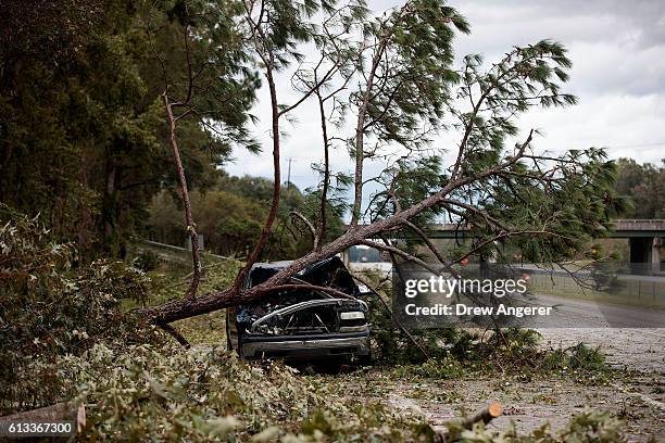 An abandoned car damaged by a fallen tree sits along Interstate 16, October 8, 2016 in Savannah, Georgia. Across the Southeast, Over 1.4 million...