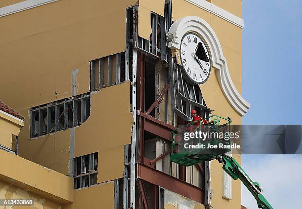 Workers inspect the damage to a building from the high winds of Hurricane Matthew on October 8, 2016 in Daytona, Florida. Across the Southeast, over...