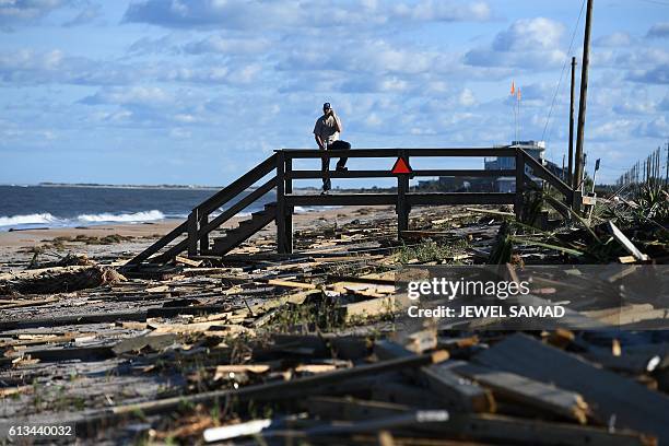 Man leans on a damaged boardwalk at a debris covered beach in St Augustine, Florida, on October 8 after Hurricane Matthew passed the area. Hurricane...