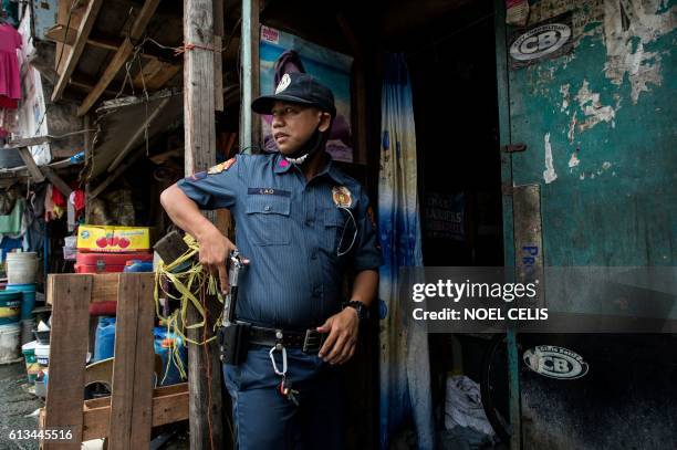 Police officers draws his gun as he is about to enter a house during an "Oplan Tokhang" or house-to-house campaign on illegal drugs at an informal...