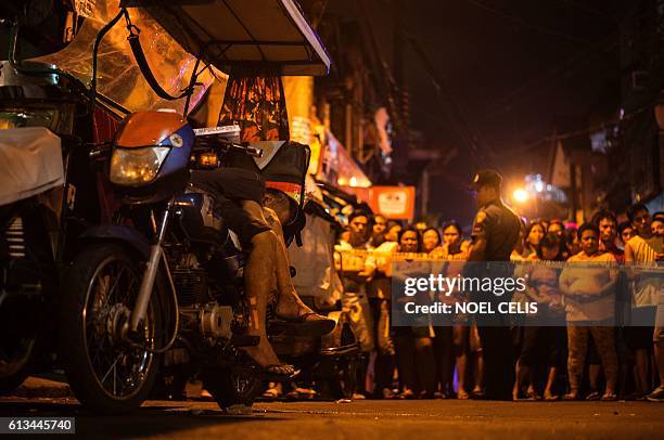 People look at a tricycle driver, which according to police officials was an alleged drug user, who was shot dead by unidentified gunmen in Manila on...