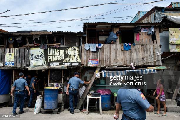 Police officers conduct an "Oplan Tokhang" or house-to-house campaign on illegal drugs at an informal settlers' community in Manila on October 6,...