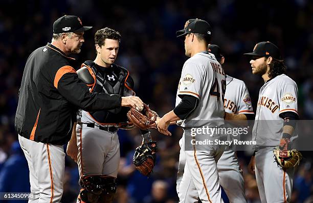 Manager Bruce Bochy of the San Francisco Giants hands the ball to Javier Lopez in the seventh inning against the Chicago Cubs at Wrigley Field on...