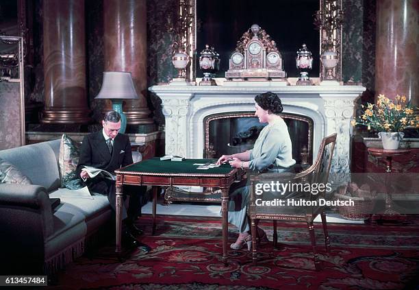 King George VI and Queen Elizabeth of England relax at home in Buckingham Palace. These pictures were taken specially to mark the occasion of their...