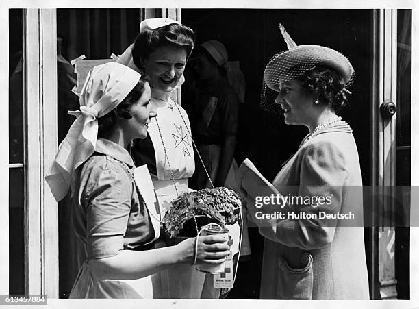 Elizabeth the queen-consort of Great Britain talks to Miss Lees and Miss O'Reilly, two nurses collecting for the Red Cross and Saint John National...