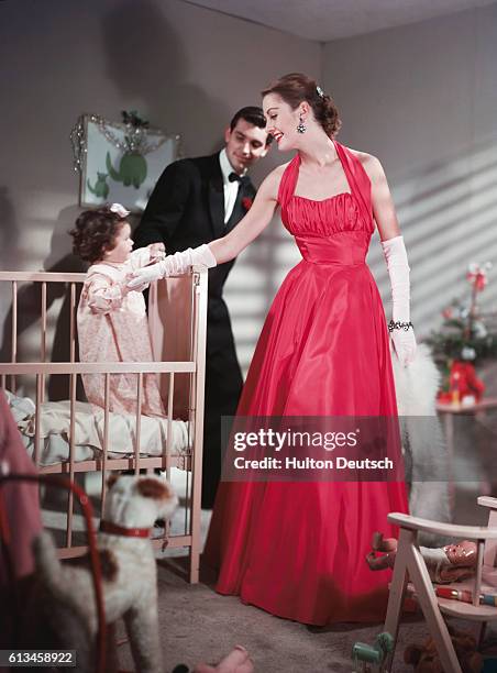 Model wears a bright pink, halter-neck eening dress, accessorized with elbow-length gloves and a fur stole.