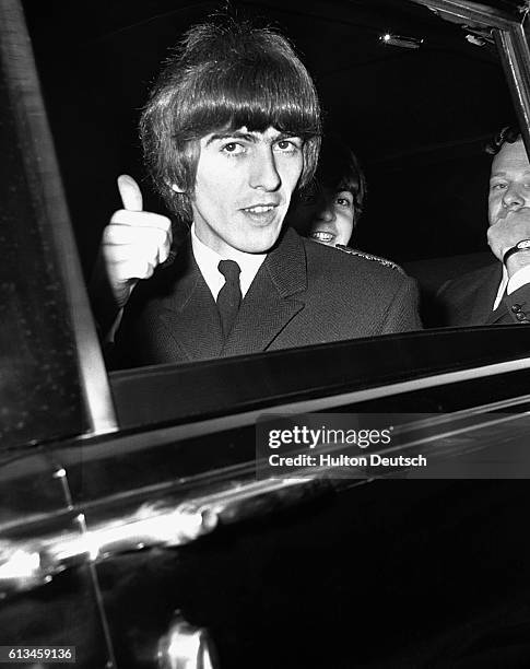 George Harrison gives the thumbs up sign as he leaves in a car for Buckingham Palace to receive his MBE from the Queen along with the three other...