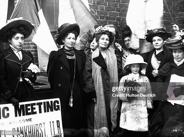 The militant campaigner for female suffrage Emmeline Pankhurst and one of her daughters are welcomed to a meeting of fellow suffragettes with banners...