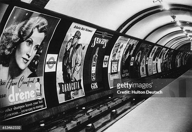 Shampoo, raincoats and gin are some of the products advertised in the posters that line the tunnel wall at the Piccadilly underground station, London...