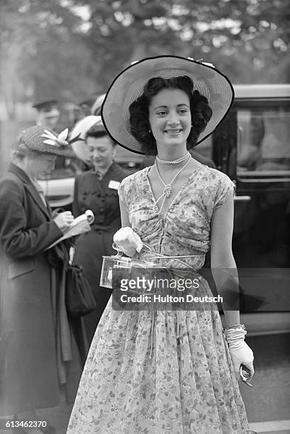 American Sondra Ritter sports a sleeveless, summer, dress accompanied with a wide-brimmed hat, and carries a see-through purse, on day one of Royal...
