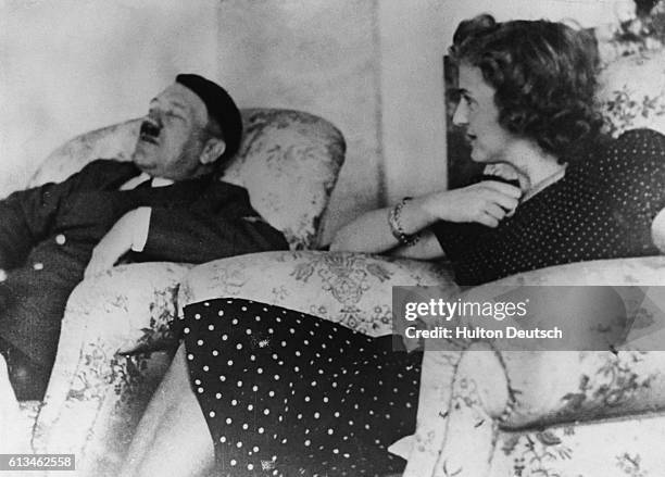 The German dictator Adolf Hitler snoozes in an armchair watched by his mistress Eva Braun.