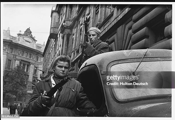 Two Hungarian freedom fighters stand armed by a truck in Budapest during the Hungarian Revolution of 1956.