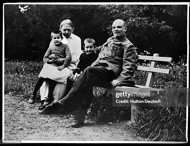 Lenin sits on a bench with his wife Krupskaya, their nephew Victor, and Vera, a worker's daughter.