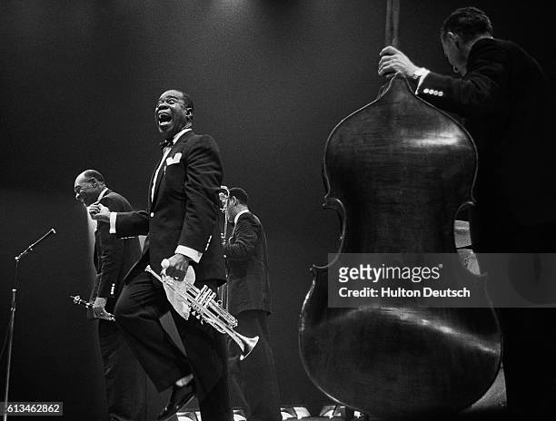 The jazz trumpeter and singer Louis Armstrong, also known as Satchmo, shouts with delight as his fellow performer Edmund Hall takes a bow after a...