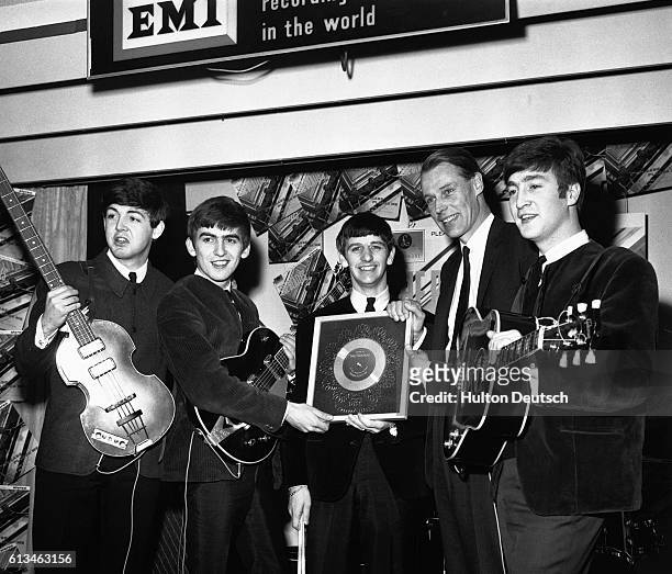 The Beatles and George Martin with the silver disc which they have been awarded after selling 1/4 million copies of their hit single Please Please Me.