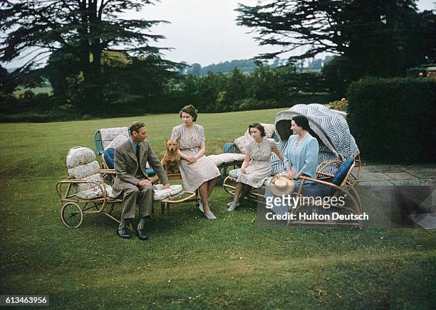 King George VI and Queen Elizabeth of England relax in the gardens of the Royal Lodge at Windsor with their daughters, Princess Elizabeth and...