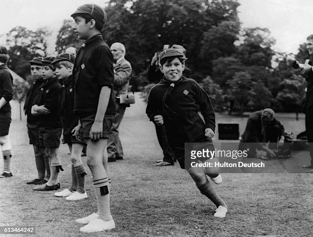 Prince Andrew, Duke of York, runs through the grounds of Buckingham palace with his tongue sticking out during his last Cub Scout meeting with the...