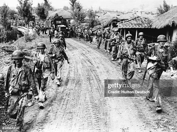 Weary, Mud Bespattered United States Troops File Through Yongsan. The scene as weary, mud bespattered American troops file along either side of the...