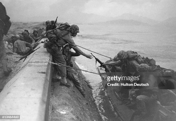 Marines climb from their landing craft at the seawall in Inchon, Korea.