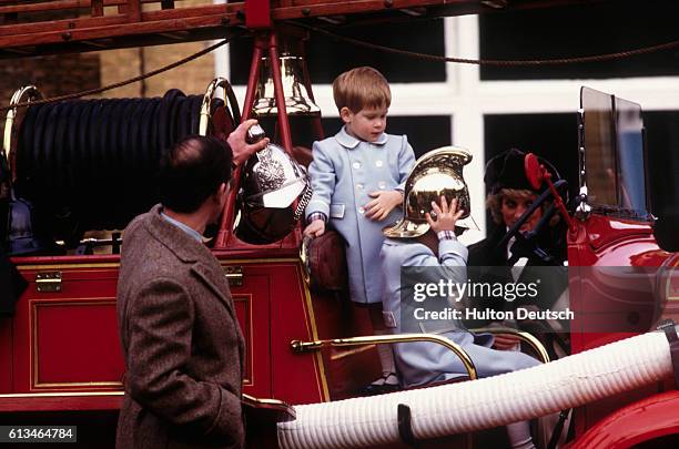 Charles, Prince of Wales, with his sons Prince Harry and Prince William who are playing on a vintage fire engine, and his wife Princess Diana at...
