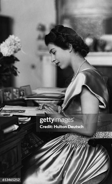 Princess Elizabeth sits reading at her private writing desk, 1947.