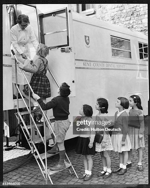 Dental assistant Mrs G.A. Hicks receives the school children as they climb the stairs to the mobile dental clinic where they will receive treatment...