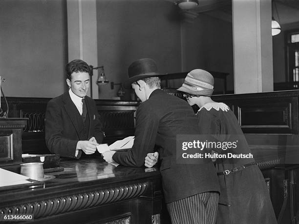 Bank clerk pays out to a young couple at the counter.