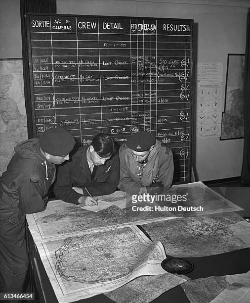 Members of the Photo Reconnaissance Unit of the Royal Air Force examine a map produced using aerial photos. | Location: Wyton, Cambridgeshire,...